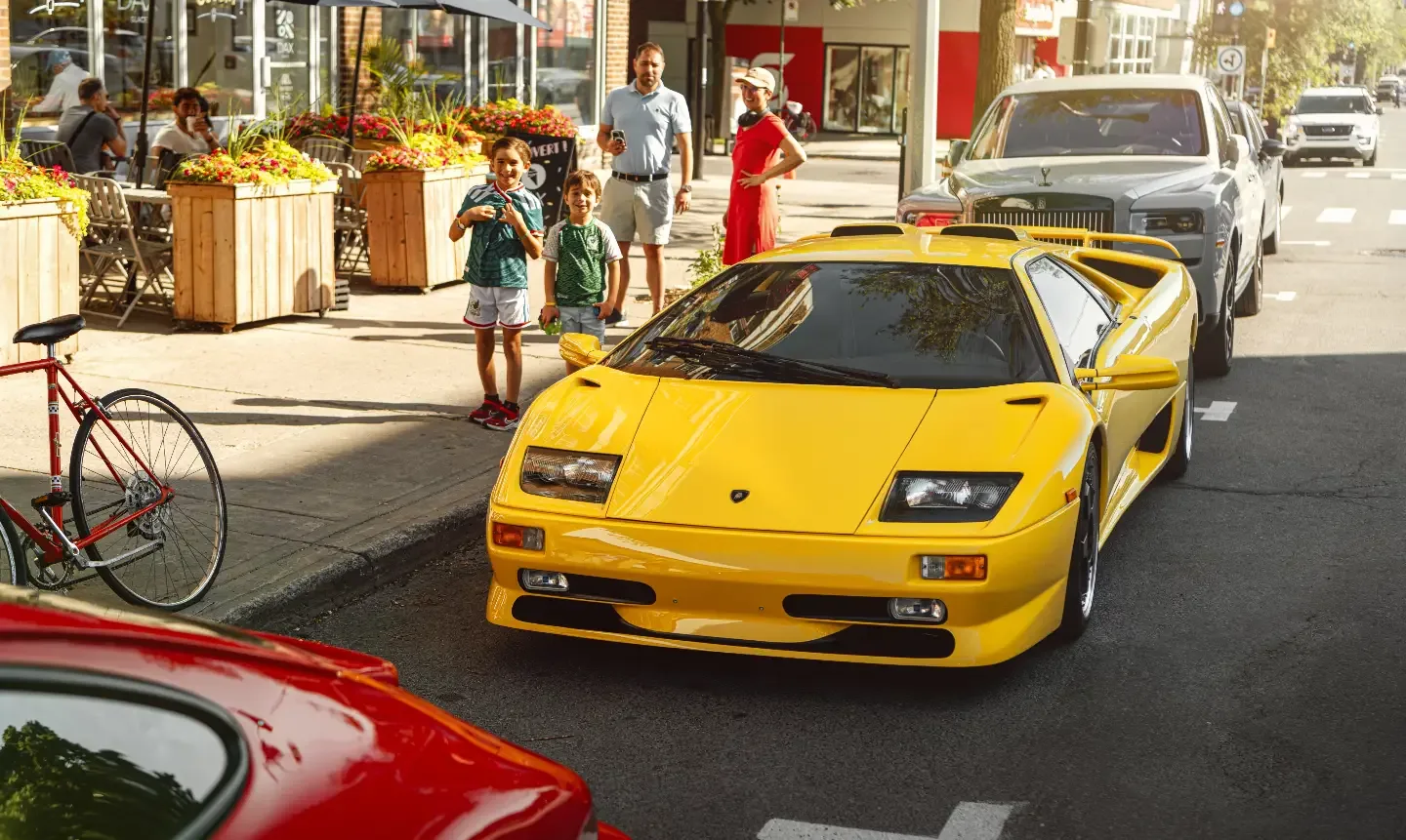 A yellow Lamborghini Diablo idles past a fruit market on Avenue Van Horne.
