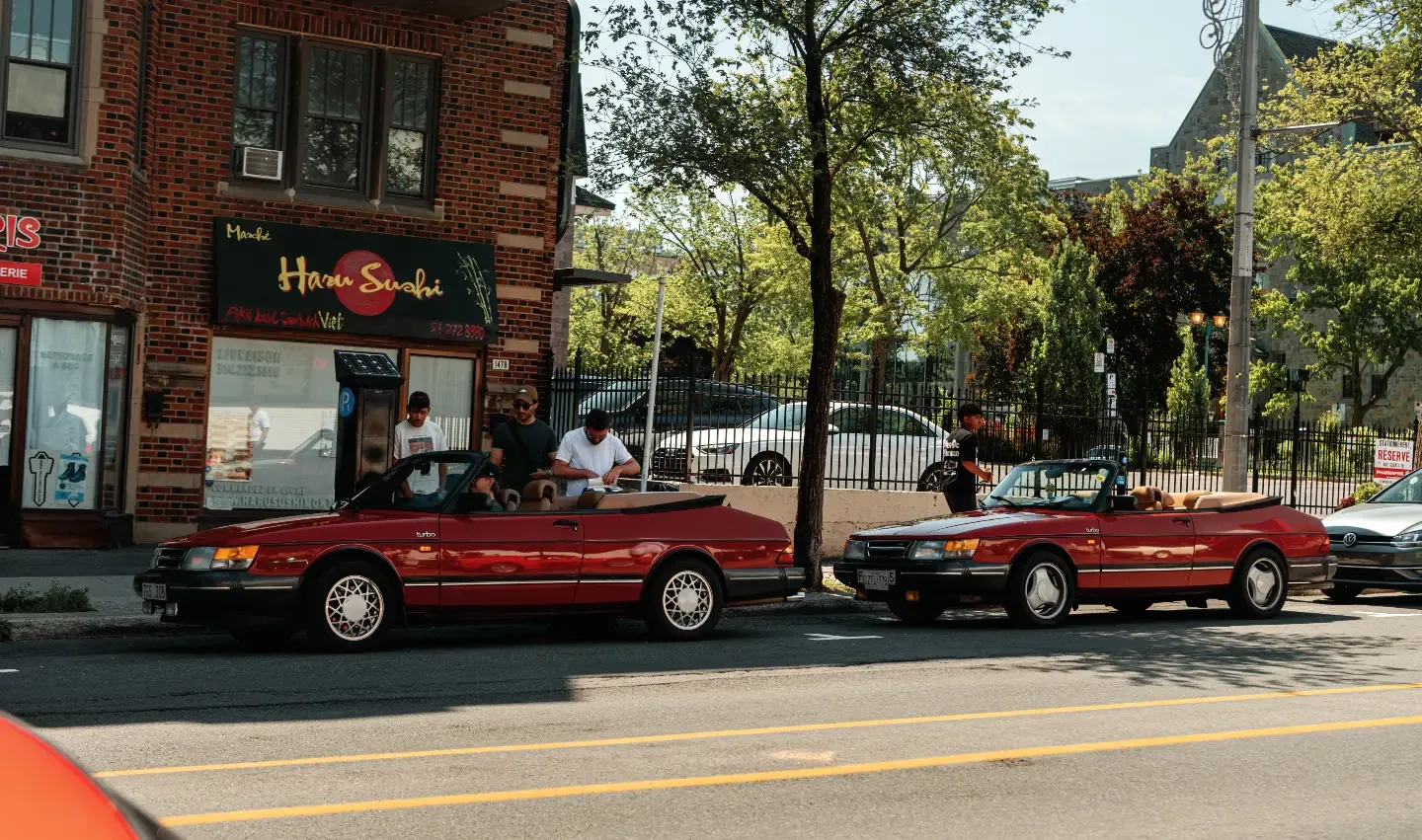 Two red Saab 900 Turbo convertibles parked nose to tail in front of a sushi counter on Avenue Van Horne.